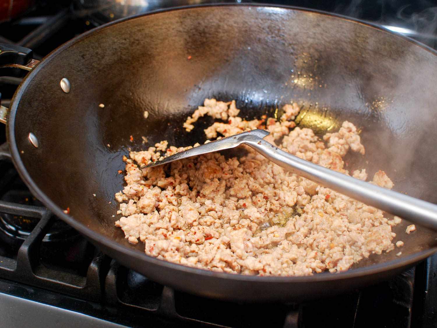 碎猪肉在锅里煎成棕色，用金属铲搅拌。