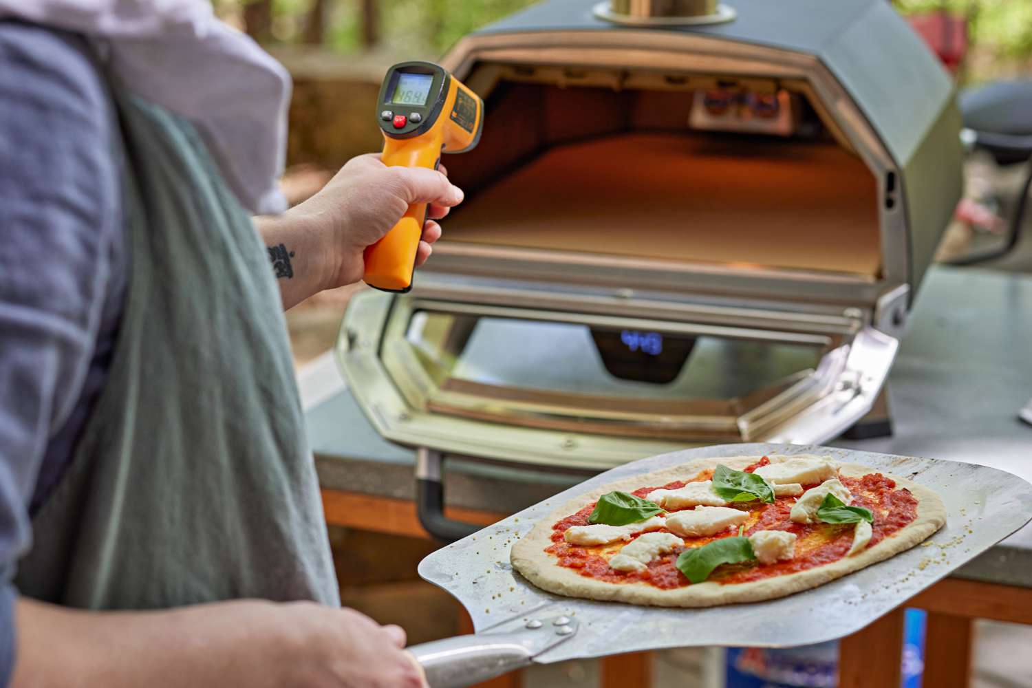 A person checking the temperature of the Ooni Karu 16 with an infrared thermometer