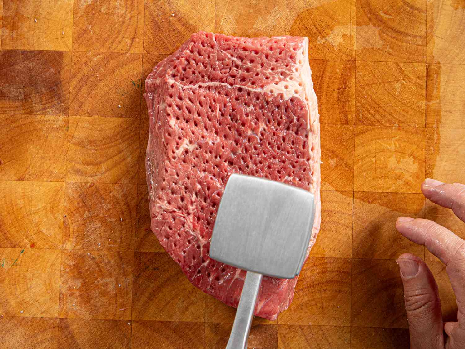 A piece of steak filled with holes during meat tenderization.