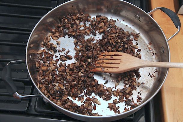 切碎的蘑菇在宽炖锅里煮熟并变成褐色。