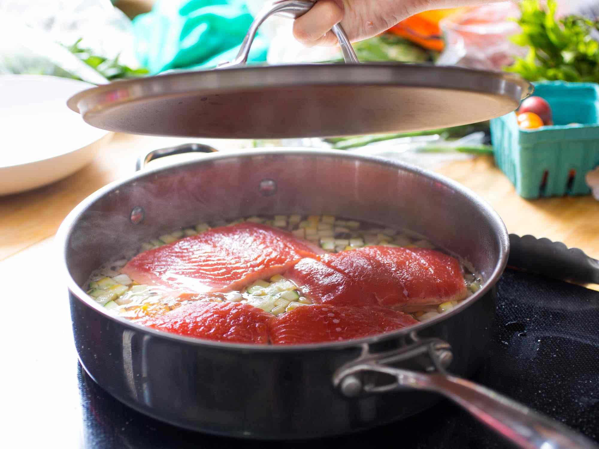 四块三文鱼片放在深边煎锅里慢慢地煎着。