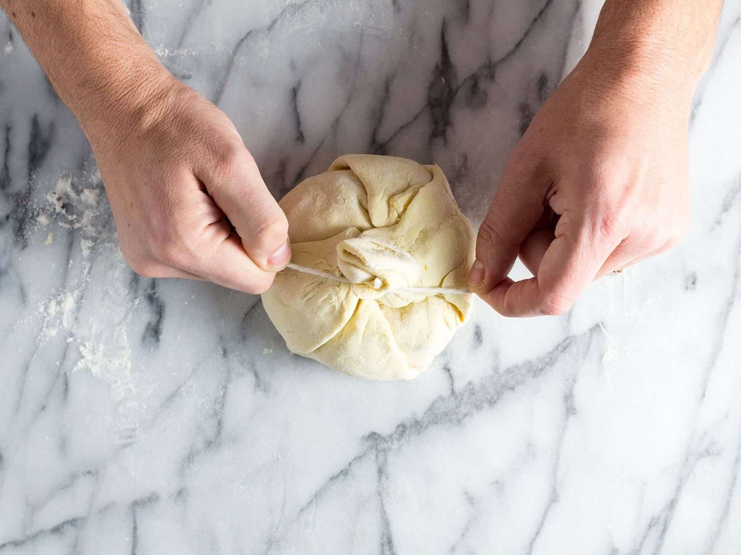 Tying a parcel of puff pastry around baked brie.
