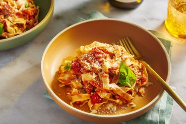 A bowl of homemade gluten-free fresh pasta with tomato sauce in an orange bowl.