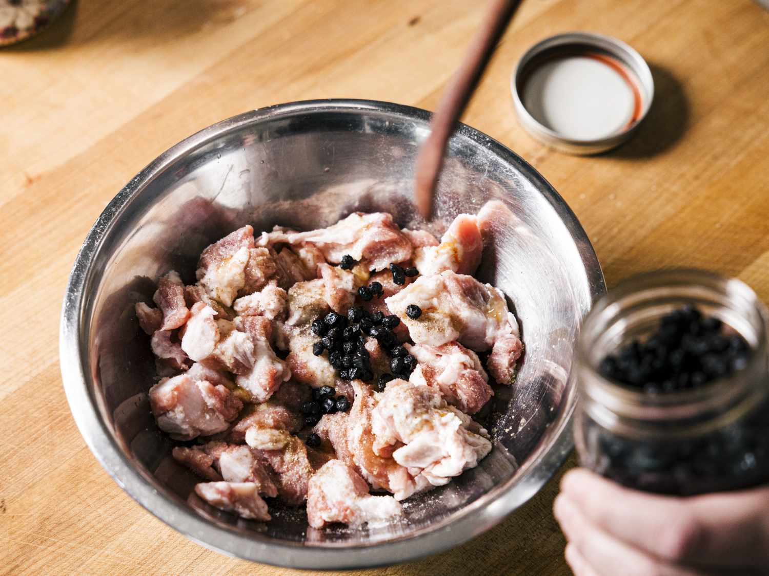在一碗猪肉中加入发酵的黑豆和其他腌料。华体会应用下载＂width=