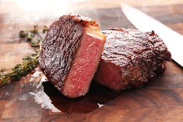 A cut sous vide-cooked steak resting on a cutting board with a knife off to the side