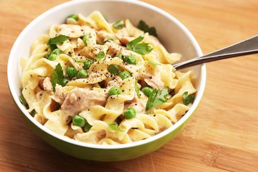 Tuna pasta with peas and fresh parsley in a bowl with a fork