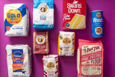 Bags of different types of flour against a purple background.