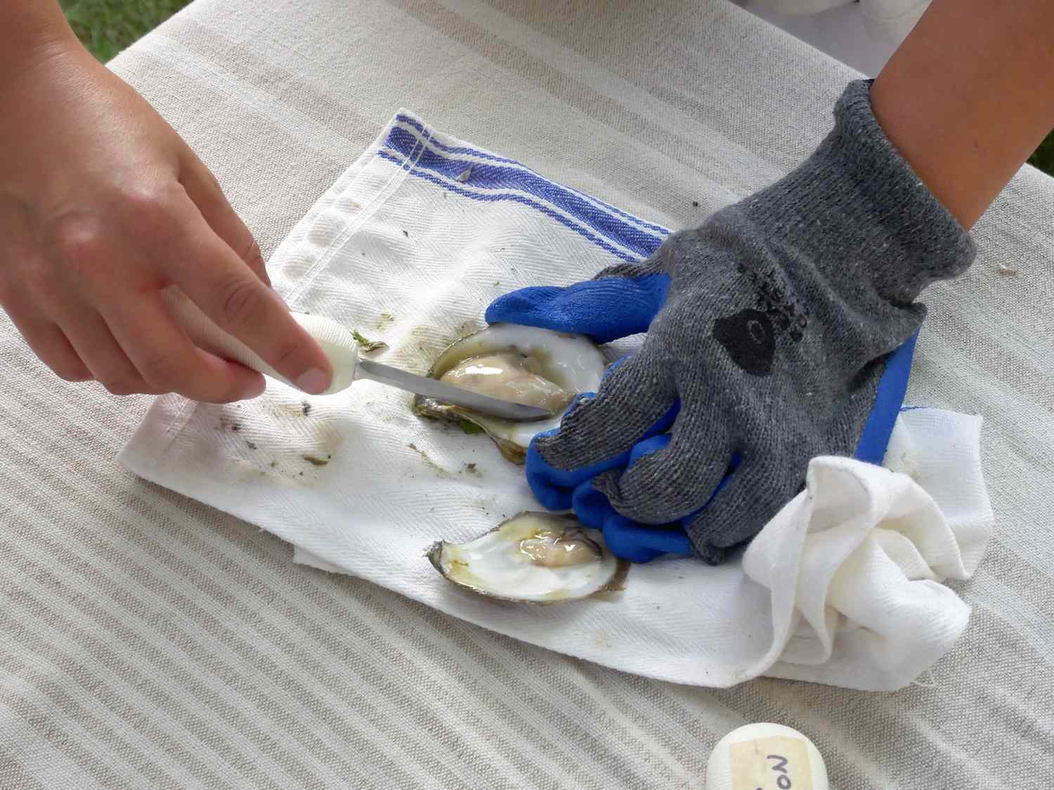 using an oyster knife to cut the oyster's abductor muscle