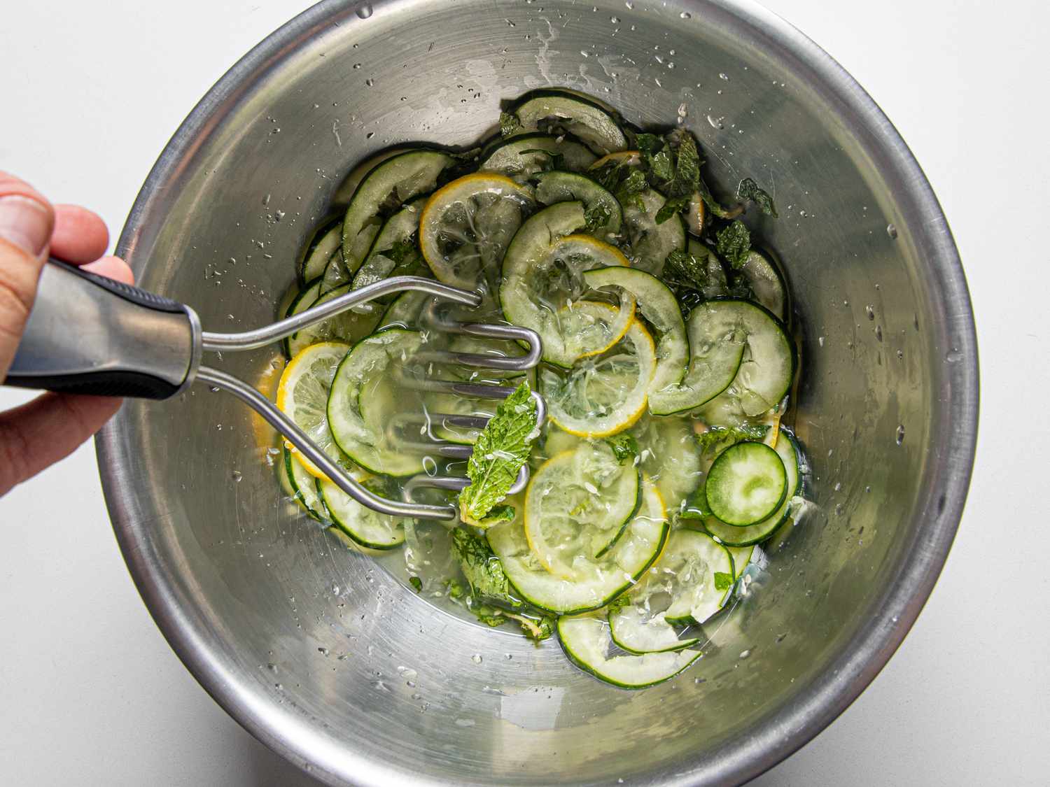 Muddling cucumbers lemon and mint