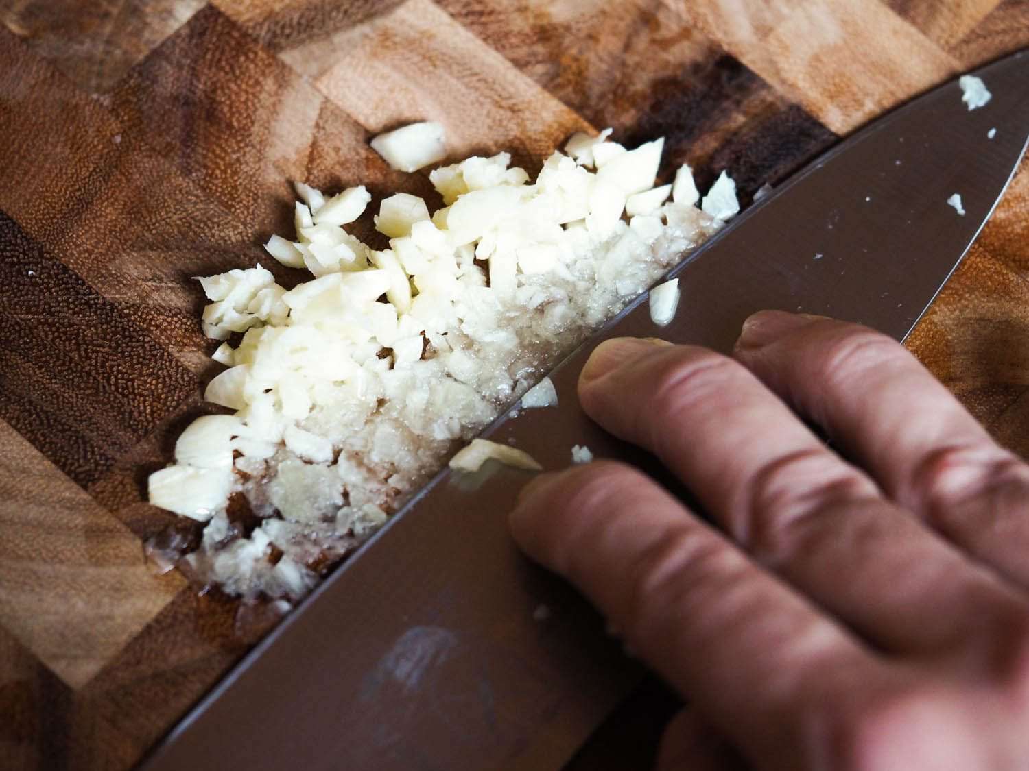 Crushing garlic with the side of a knife.