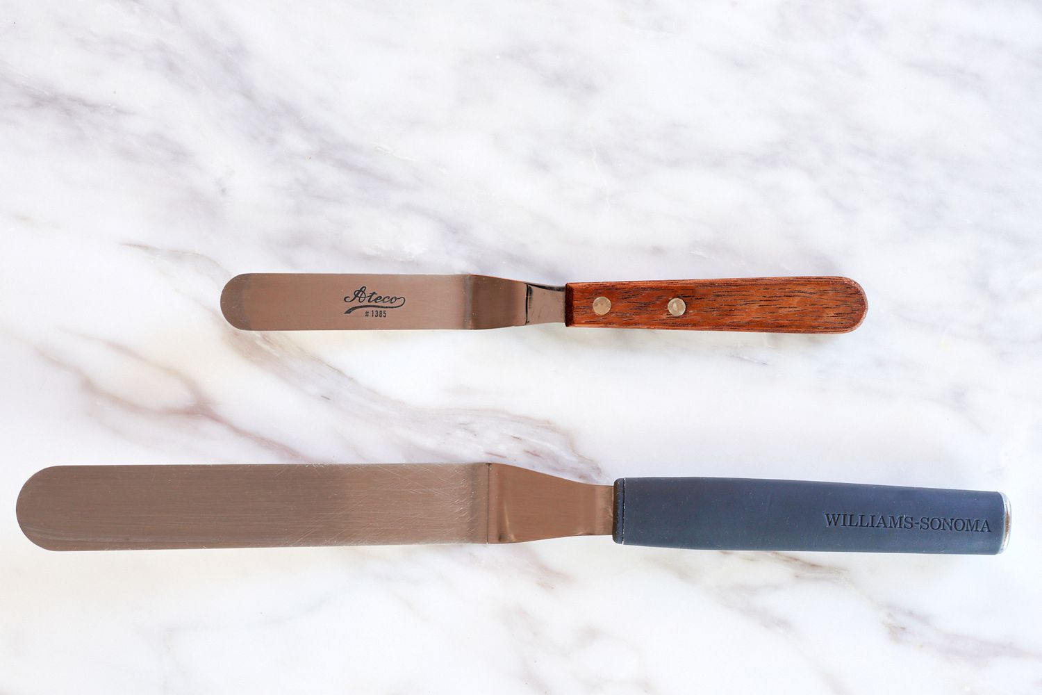 two differently sized offset spatulas on a marble surface