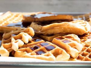 Close-up of various types of waffles with syrup on a metal sheet pan