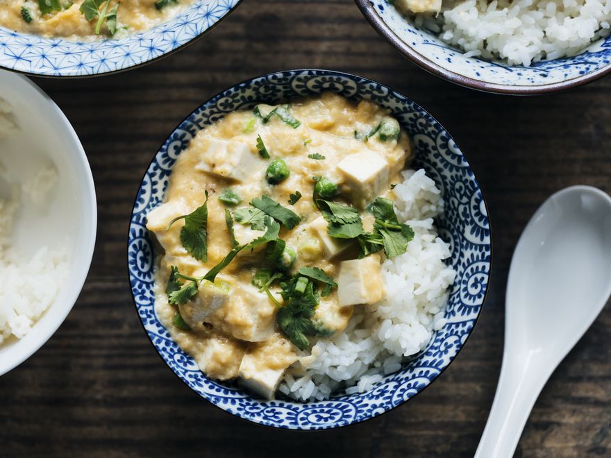 俯视图:滑滑的鸡蛋，豆腐和豌豆放在一个蓝色图案的碗里