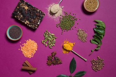 Overhead view of Indian pantry items arranged on a fuchsia surface.
