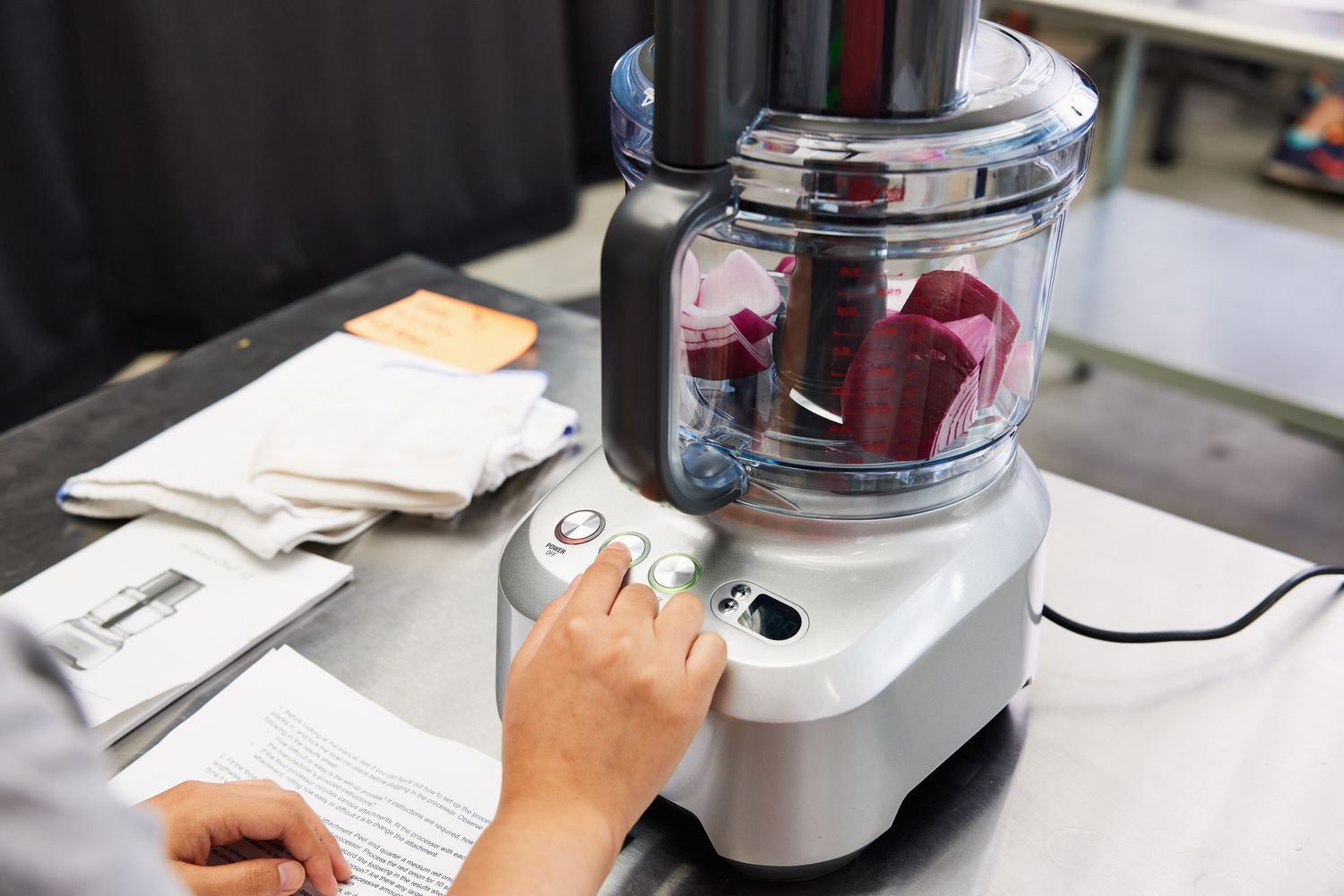 A person turning on a food processor with onions inside of it