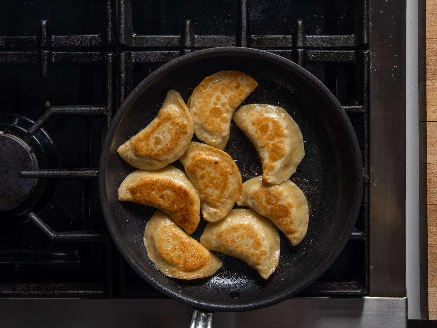 Pierogi crisping in a skillet with butter and oil.