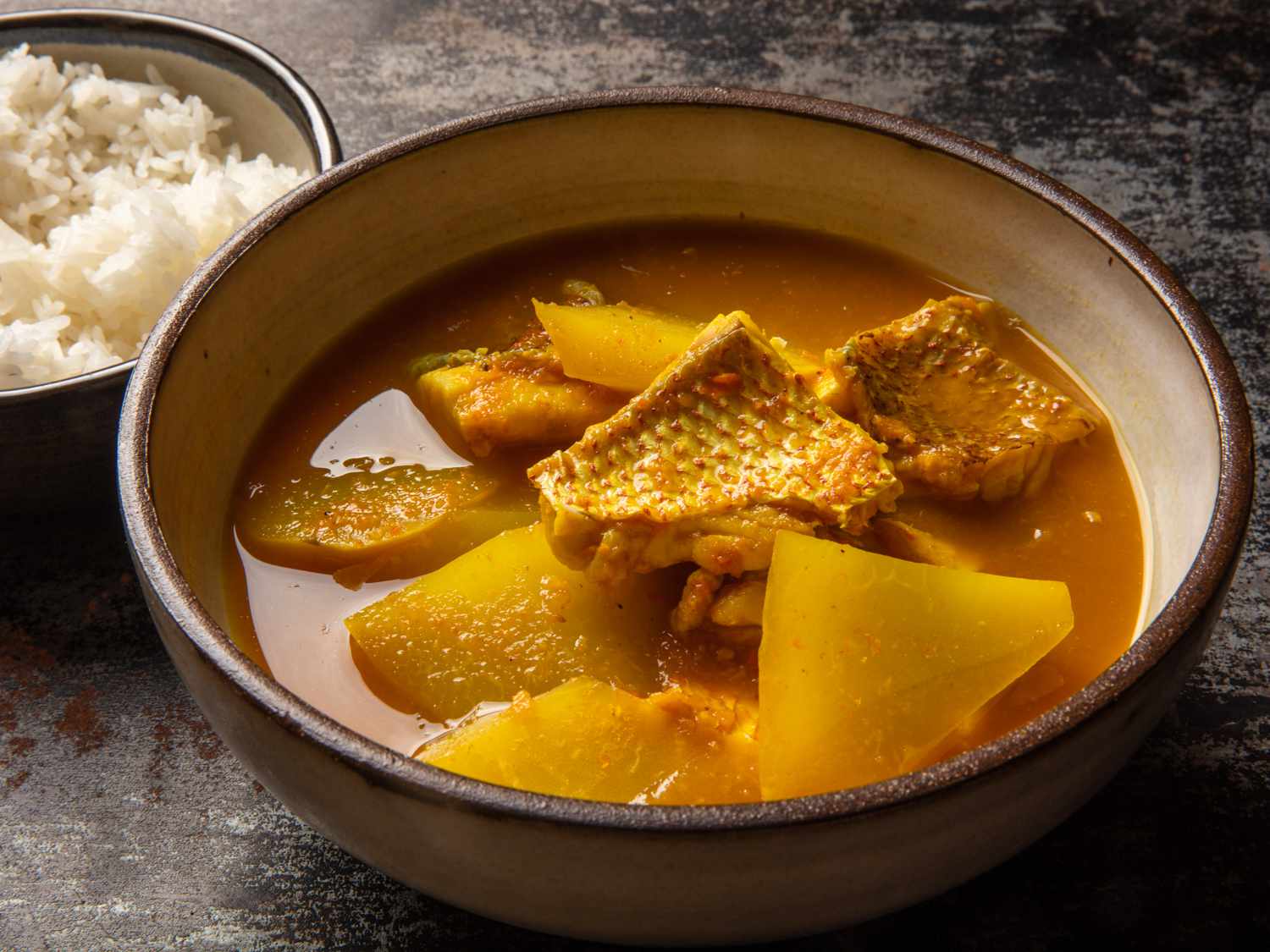 a side view of Gaeng Som Pla Gapohng Daeng (Southern Thai Sour Curry with Red Snapper and Green Papaya)