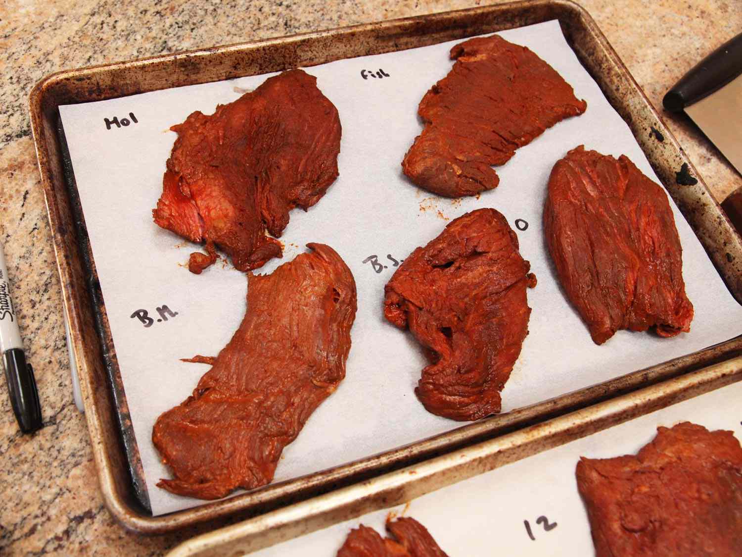 用各种风味增强剂在羊皮纸衬里的烤盘上腌制的牛排，然后烤肉酱。