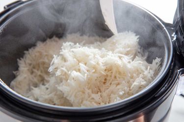 Steam escaping from the open lid of a Hamilton Beach rice cooker filled with cooked rice