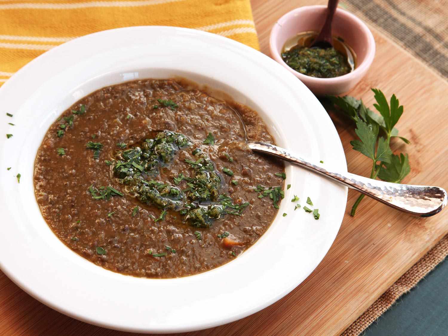A bowl of lentil soup garnished with chopped herbs and gremolata