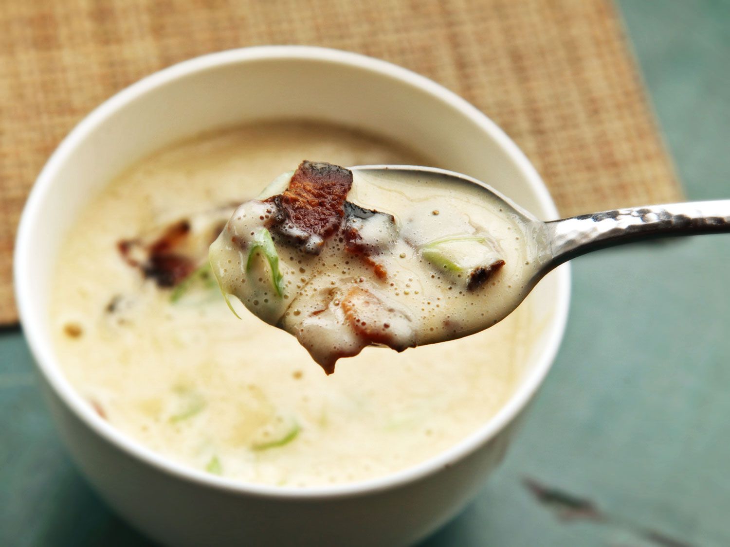 一勺奶油花椰菜汤和培根从一个白色的碗