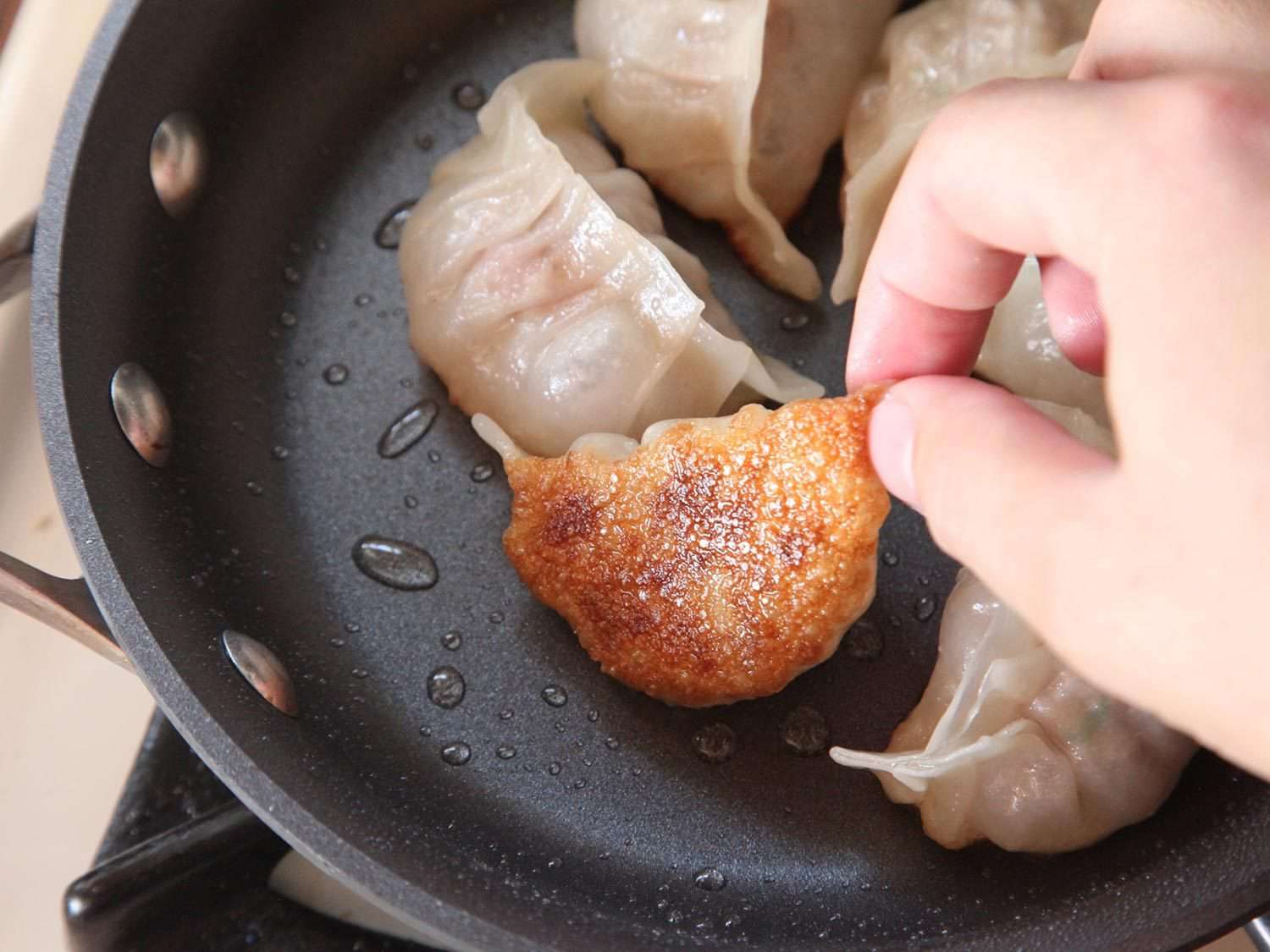 在平底锅里翻一个脆底饺子。