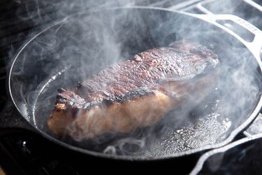 A peanut butter sous vide steak searing in a cast iron skillet.