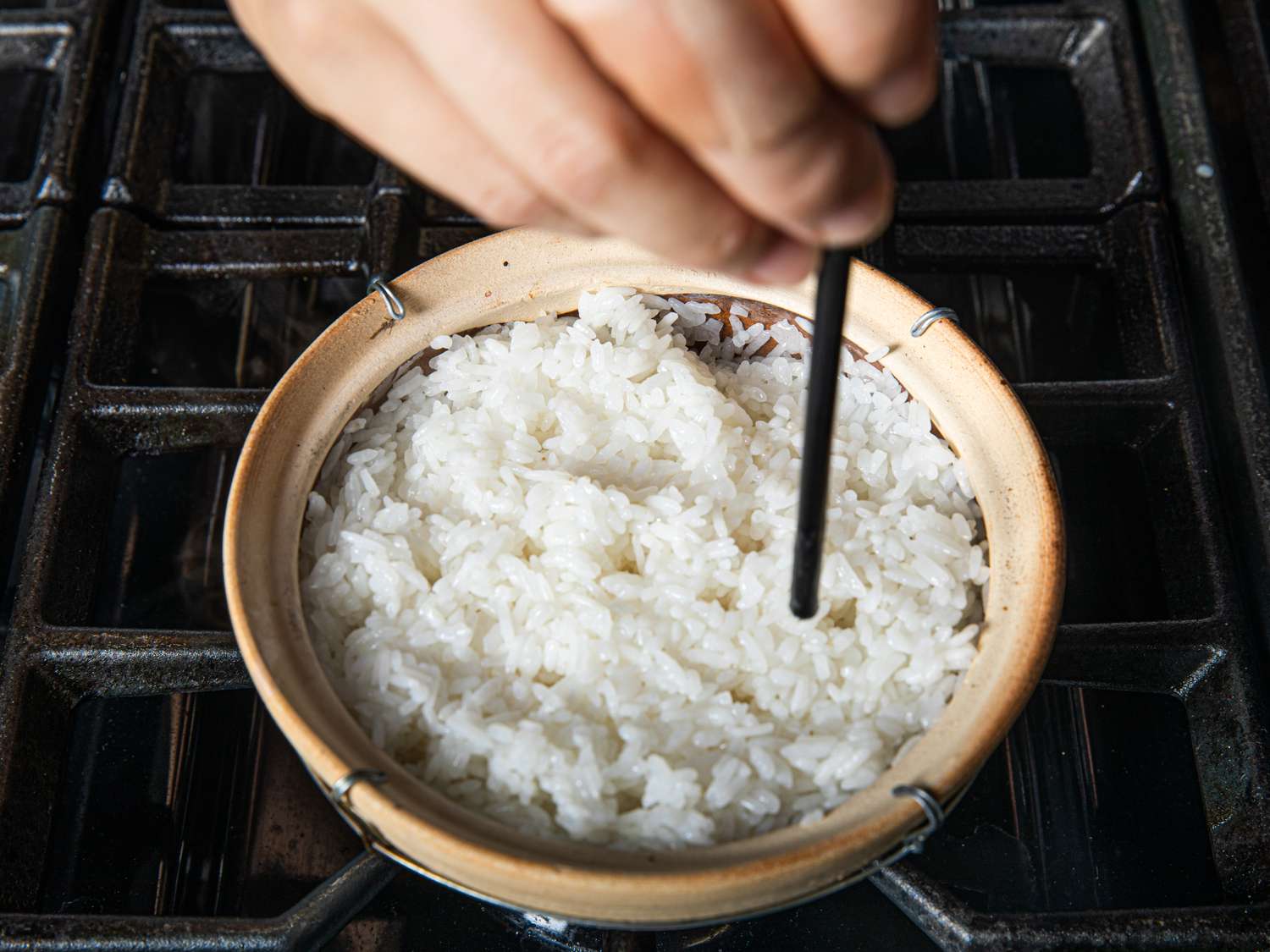 Poking holes in rice that's being cooked in a Cantonese clay pot.