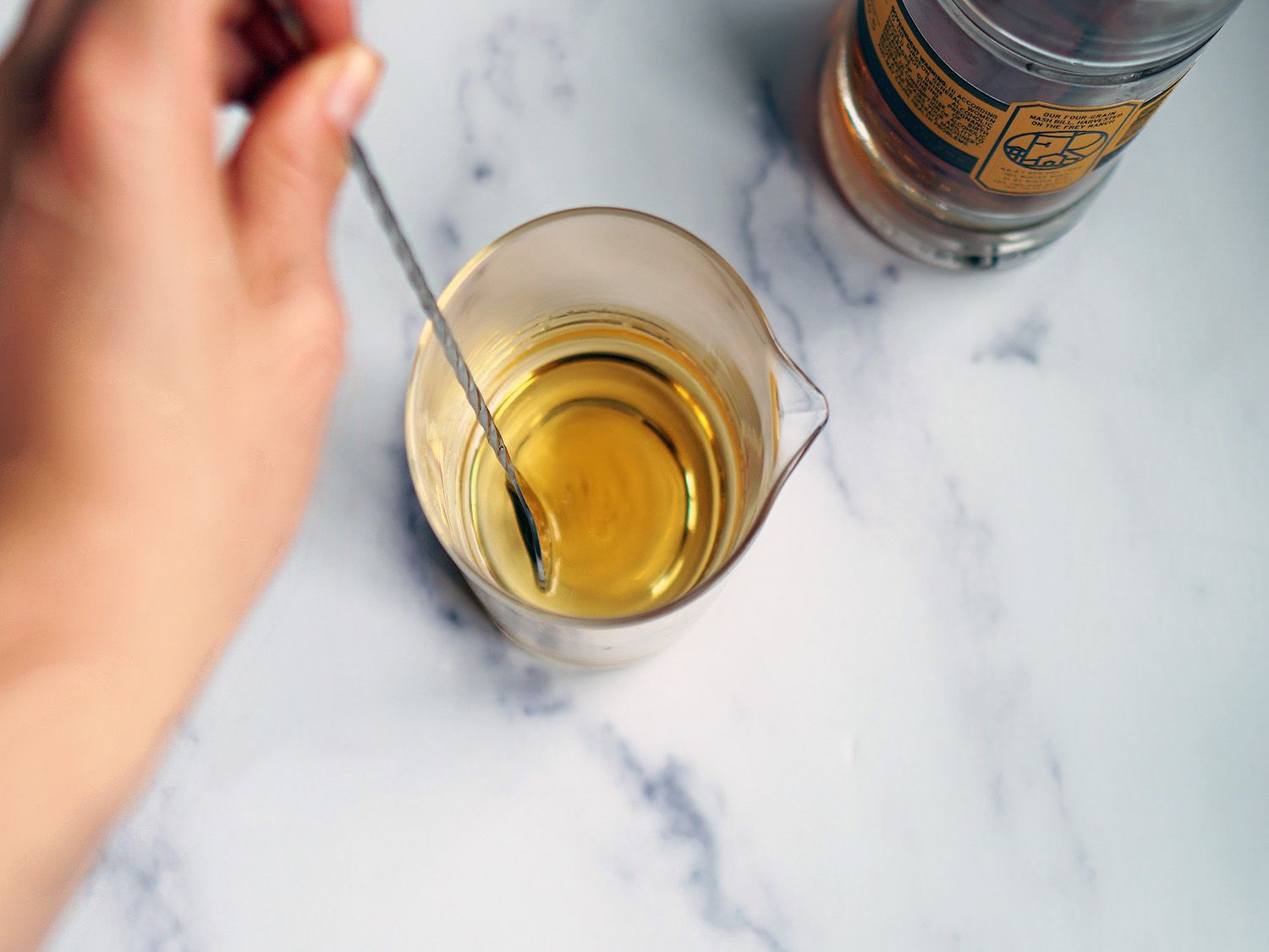 an overhead look at a hand using a bar spoon to stir a cocktail