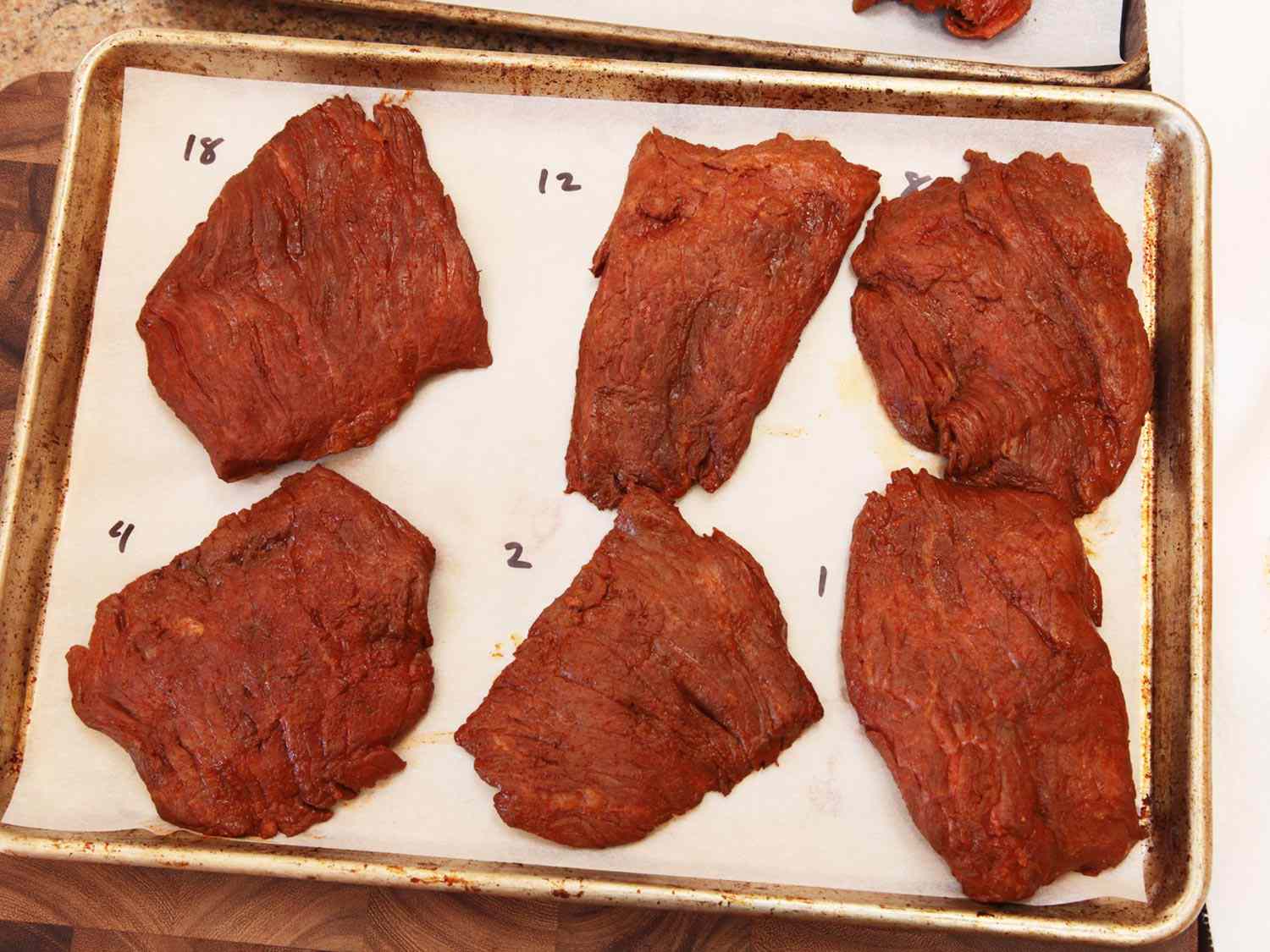 用羊皮纸衬里的平底锅，上面放着六块牛排，每一块都腌制了不同的时间，然后烤成浅肉。