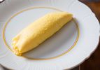 A classic French omelette on an elegant white plate.