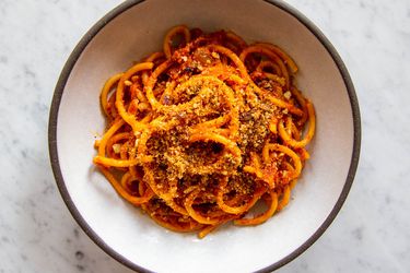 A white bowl with a dark gray rim holding a serving of Sicilian Pasta With Anchovies and Toasted Breadcrumbs, Pasta c'Anciuova e Muddica Atturrata