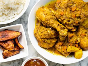 Overhead view of curry chicken with rice and fried plantains