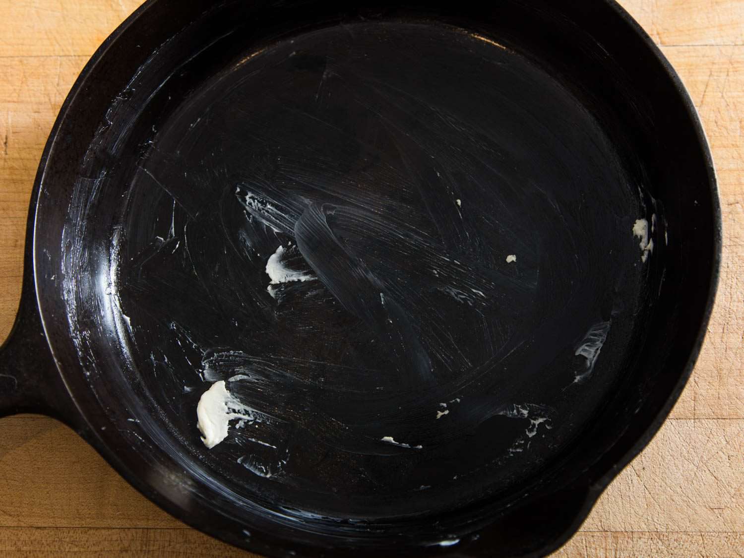 Overhead view of a buttered cast iron skillet.