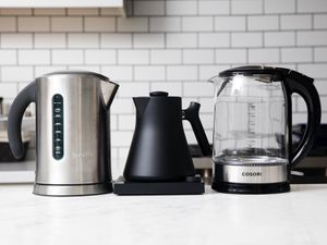 three electric kettles on a marble kitchen countertop