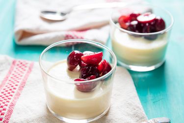 Glass cups filled with vanilla panna cotta and fresh cherries.