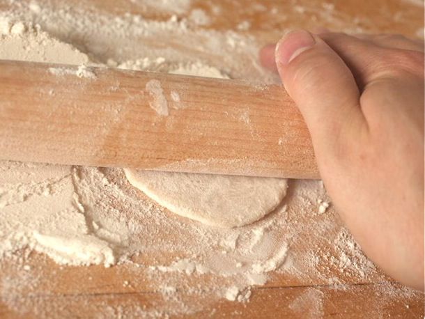 Author rolling out rounds of dough on a well-floured cutting board with a rolling pin.