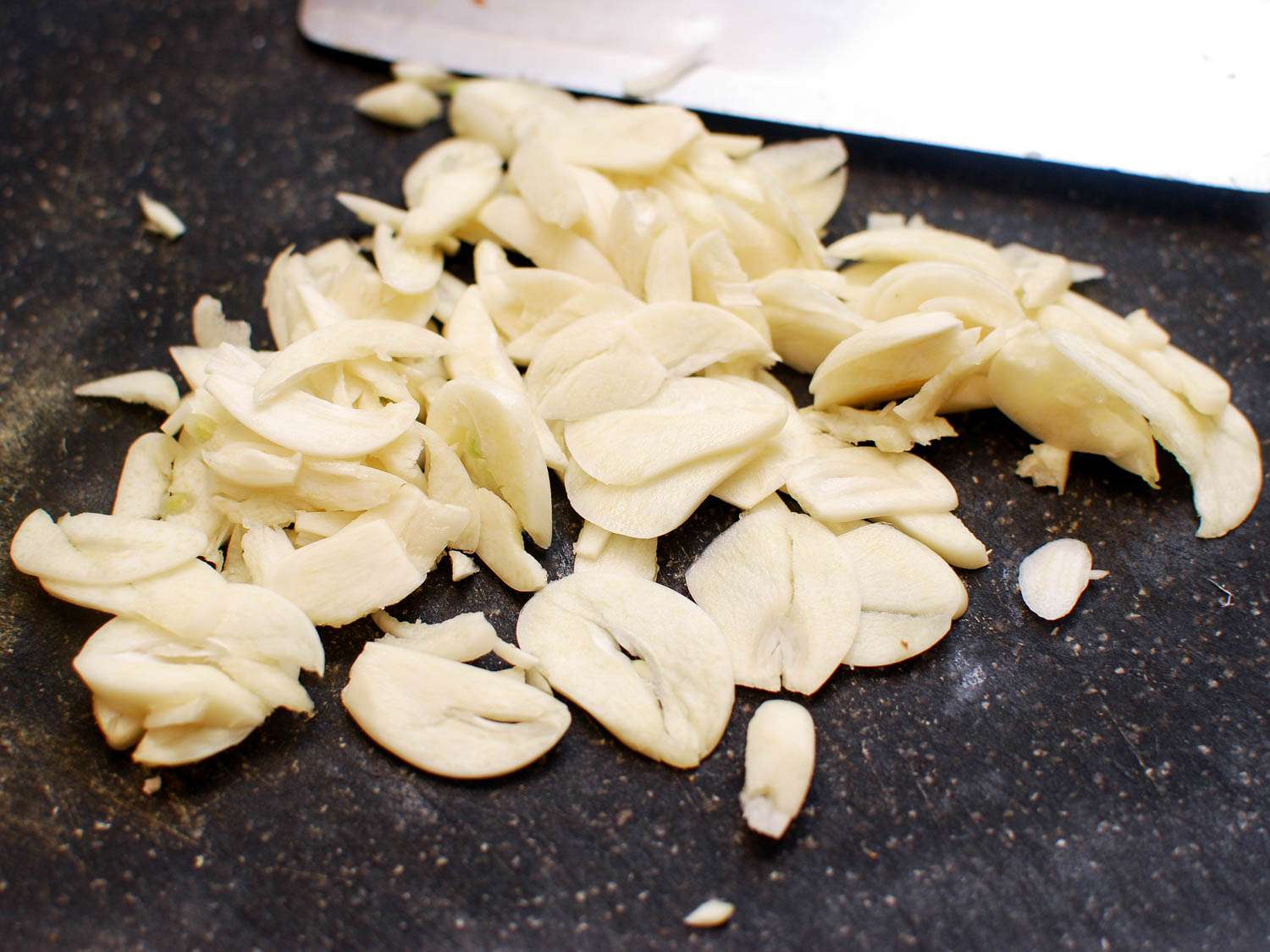 切菜板上放一堆切片大蒜，准备下锅。