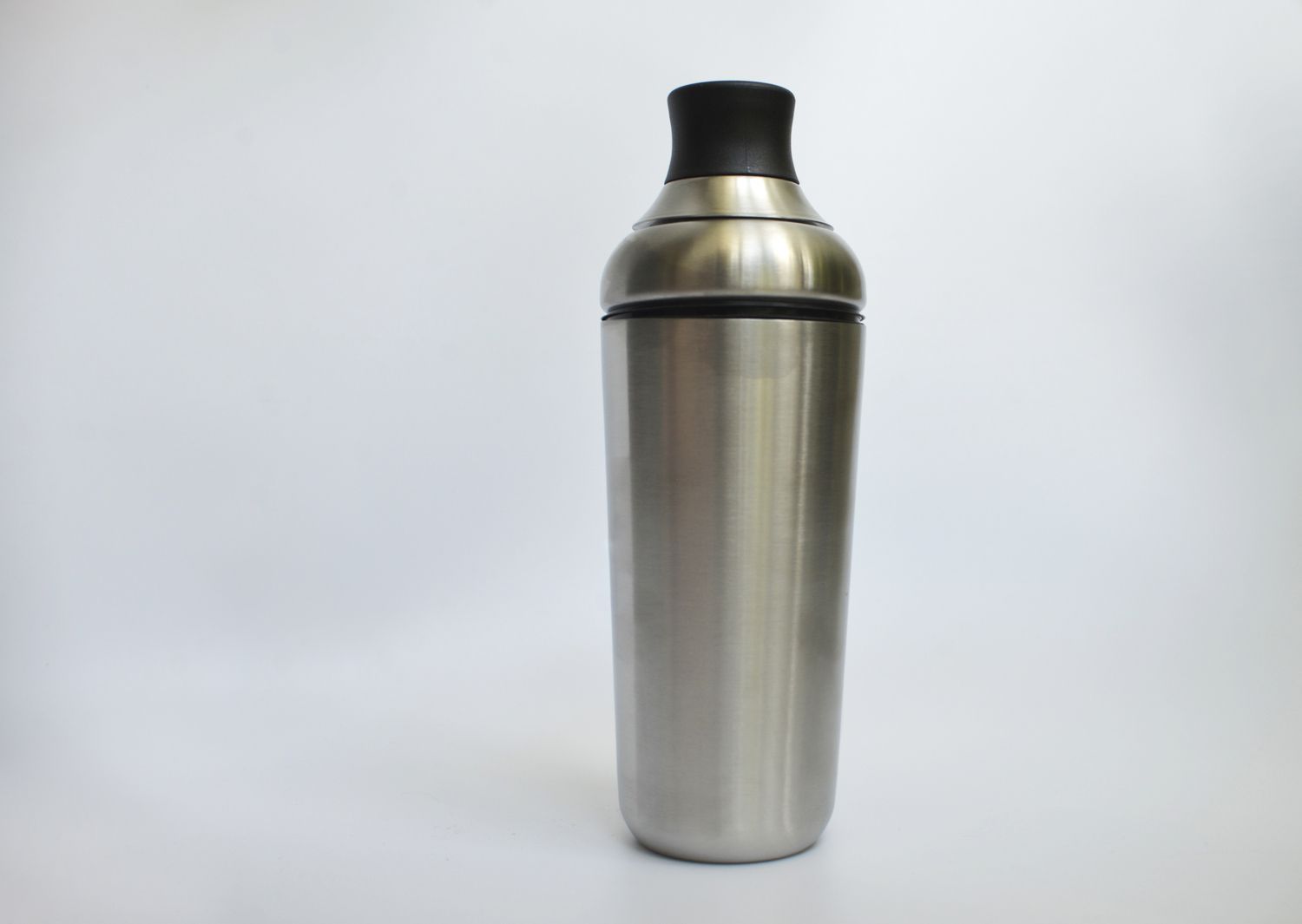 a stainless steel cobbler shaker with a silicone cap on a white surface and against a white background