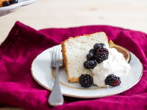 slice of angel food cake plated with chantilly cream, fresh fig, blueberries, and blackberries