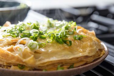 A layered Chinese-style omelette, topped with scallions.