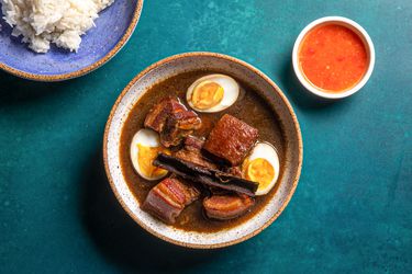 Overhead shot of finished moo palo with cut open eggs, dipping sauce, and a plate of rice