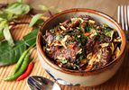 陶制的碗里盛着泰式牛肉，佐以罗勒和辣椒。