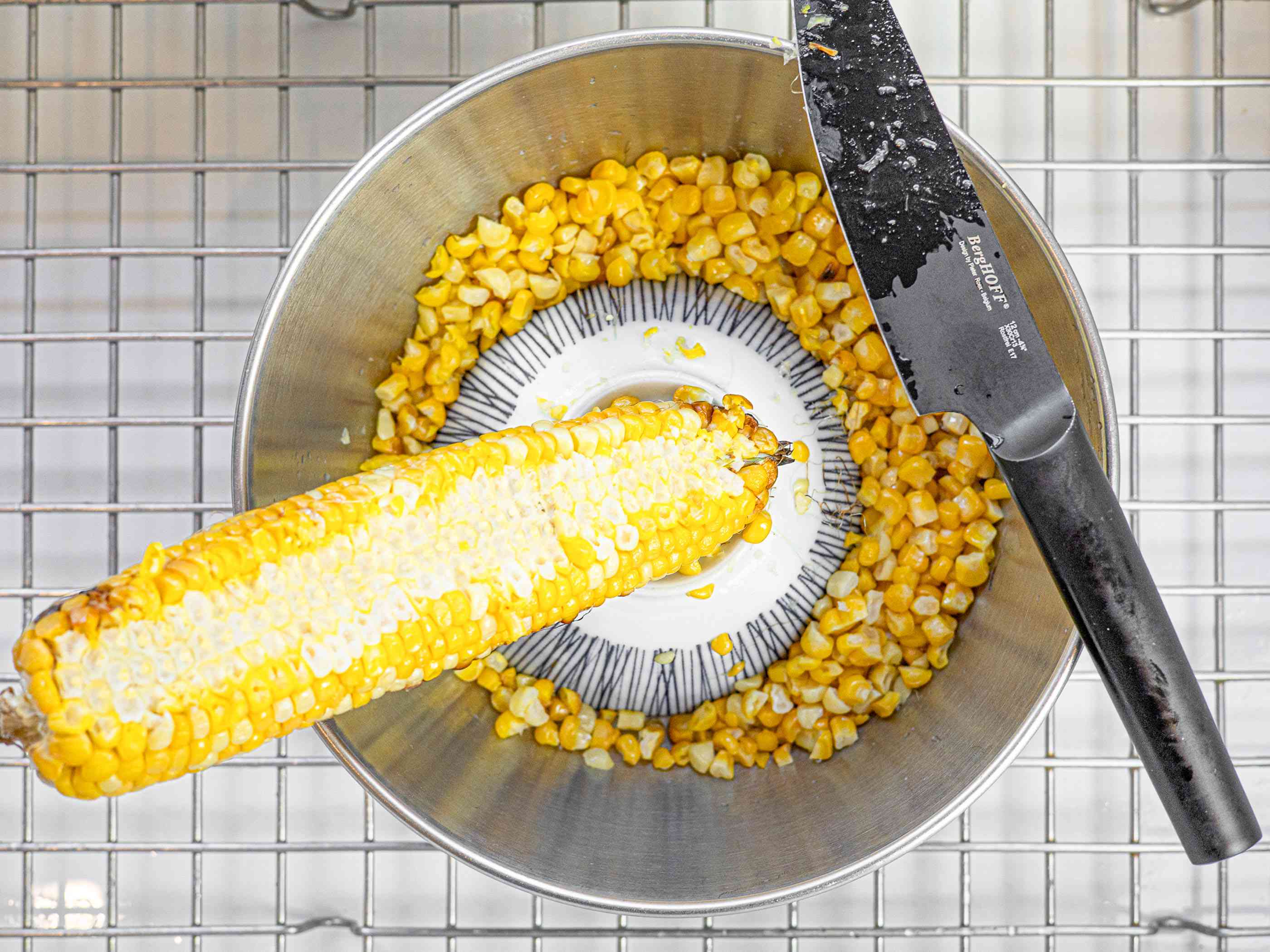 烤玉米棒平衡在一个小碗倒在一个大搅拌碗与刀平衡在大搅拌碗的唇