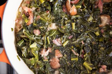 A container of braised collard greens with ham hocks.