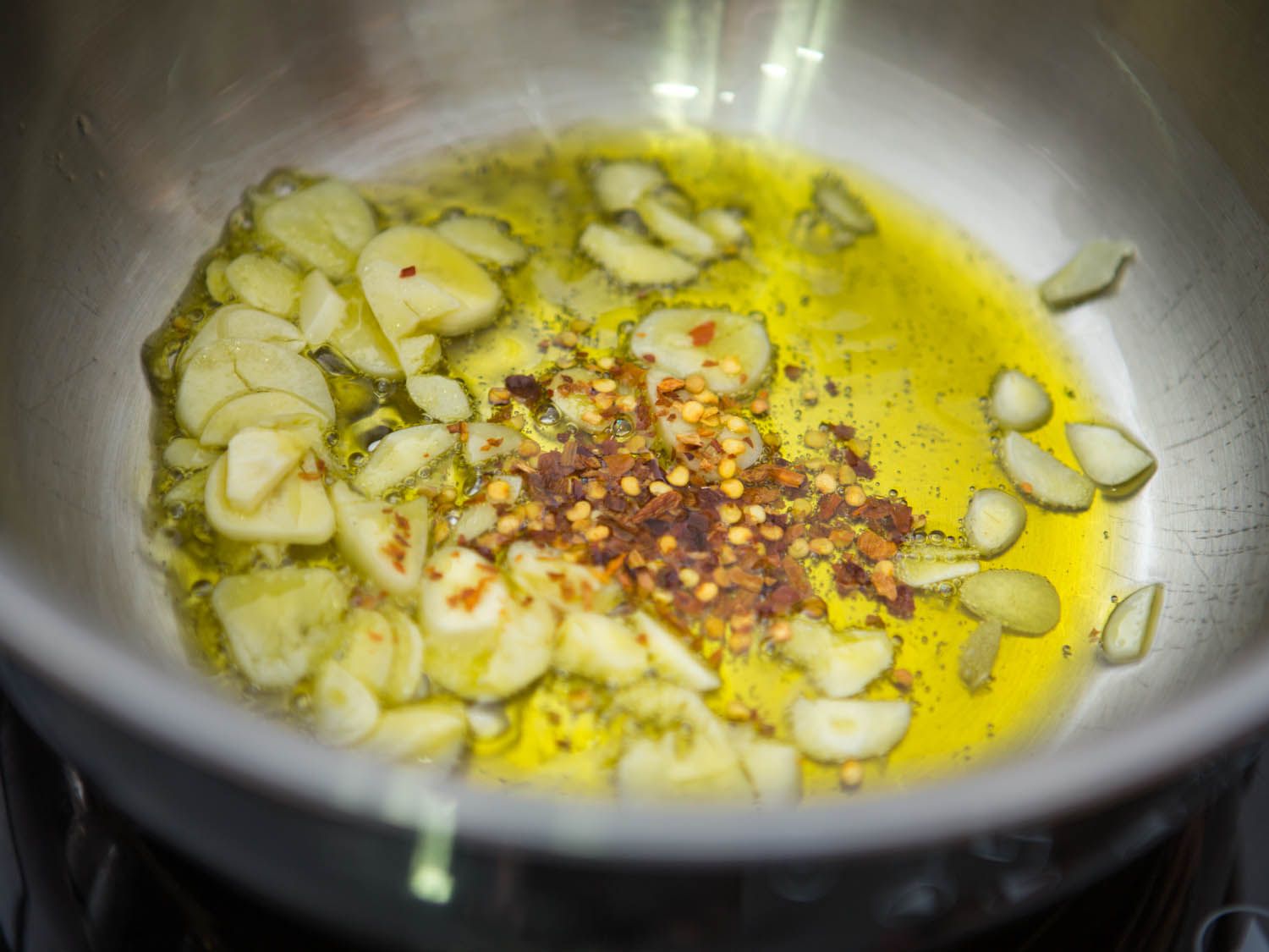 切好的大蒜和红辣椒片放入橄榄油中，放入不锈钢碗中。