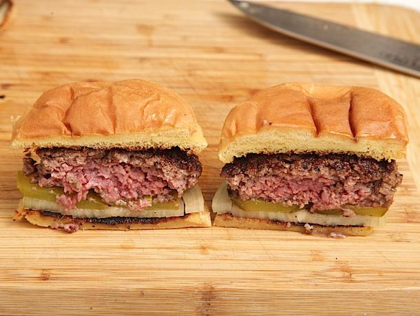两个较厚的汉堡，一个用粗碎牛肉做的，另一个用细碎牛肉做的。它们被切成两半，以显示肉饼的内部纹理。