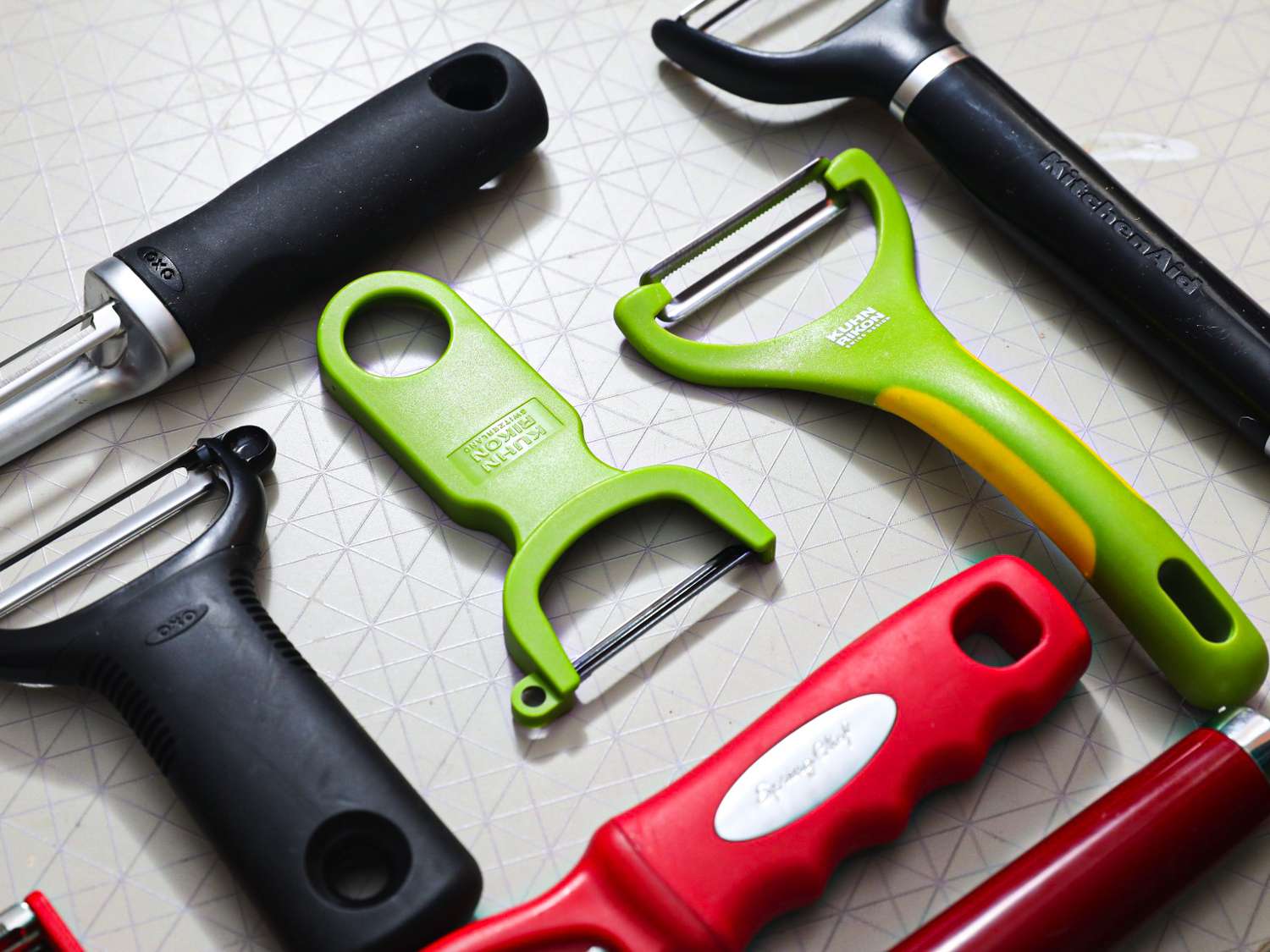 A closeup look at some vegetable peelers on a grey surface