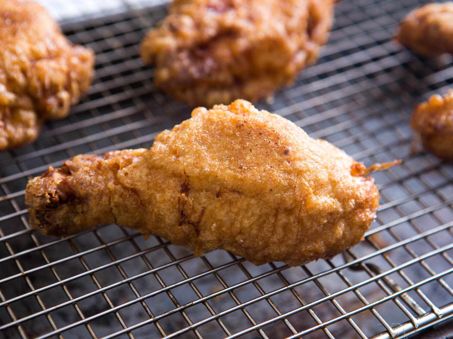 Fried chicken resting on a wire rack set in a baking sheet