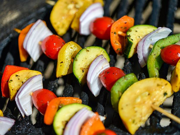 Skewers of raw vegetables on a charcoal grill.